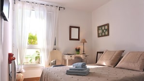 A bedroom with a bed, a desk, a chair, and a window with curtains. - B&B La Petite Maison (Marseille)