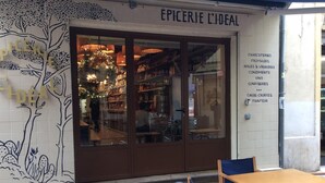 A storefront with a sign reading "EPICERIE L'IDEAL" and a list of products including charcuteries, fromages, and confiseries. - B&B La Petite Maison (Marseille)