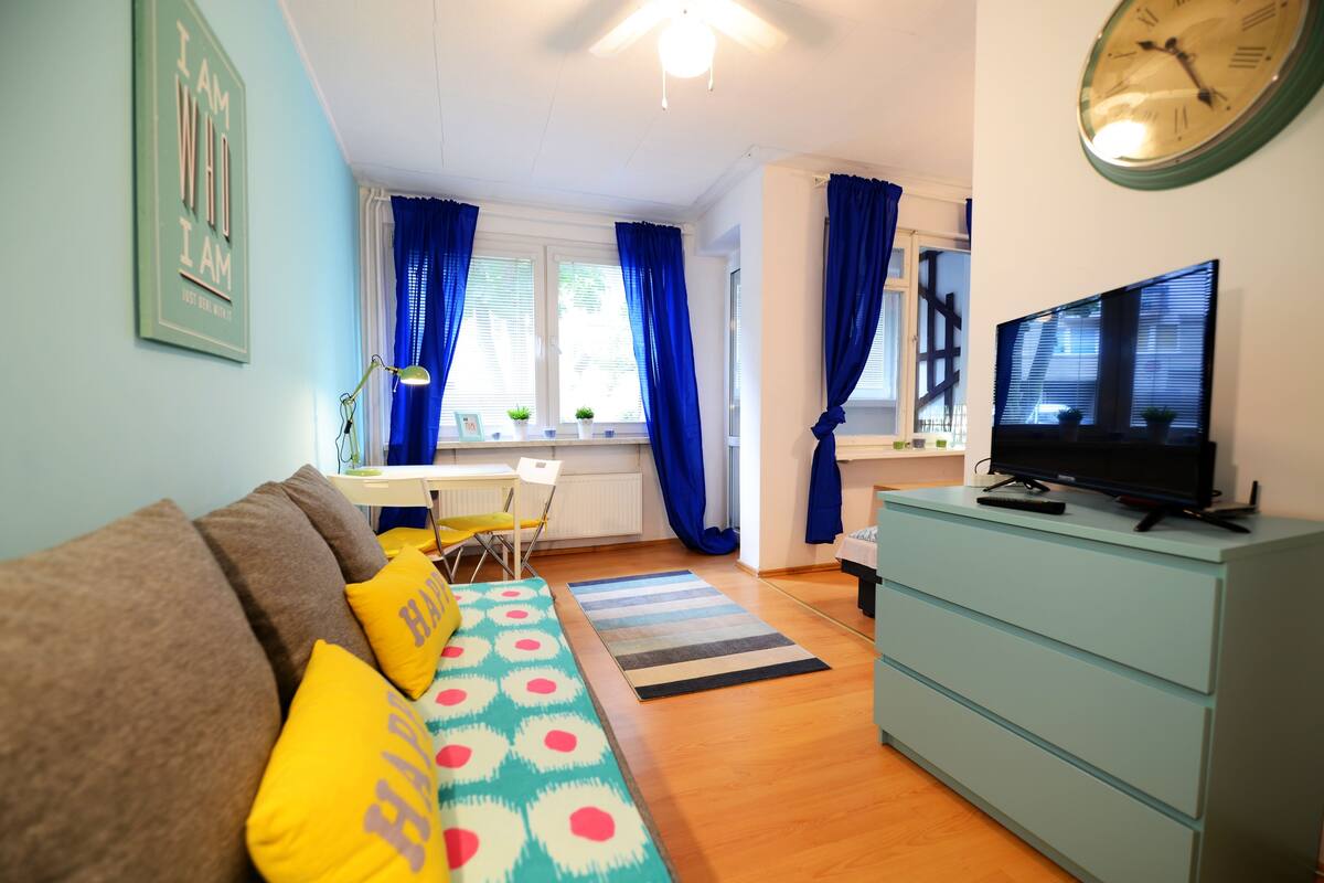 A cozy living room with a sofa, TV, and a dining area with a table and chairs.
