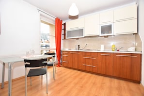 A modern kitchen with wooden cabinets, a stainless steel sink, and a dining area with a table and chairs.