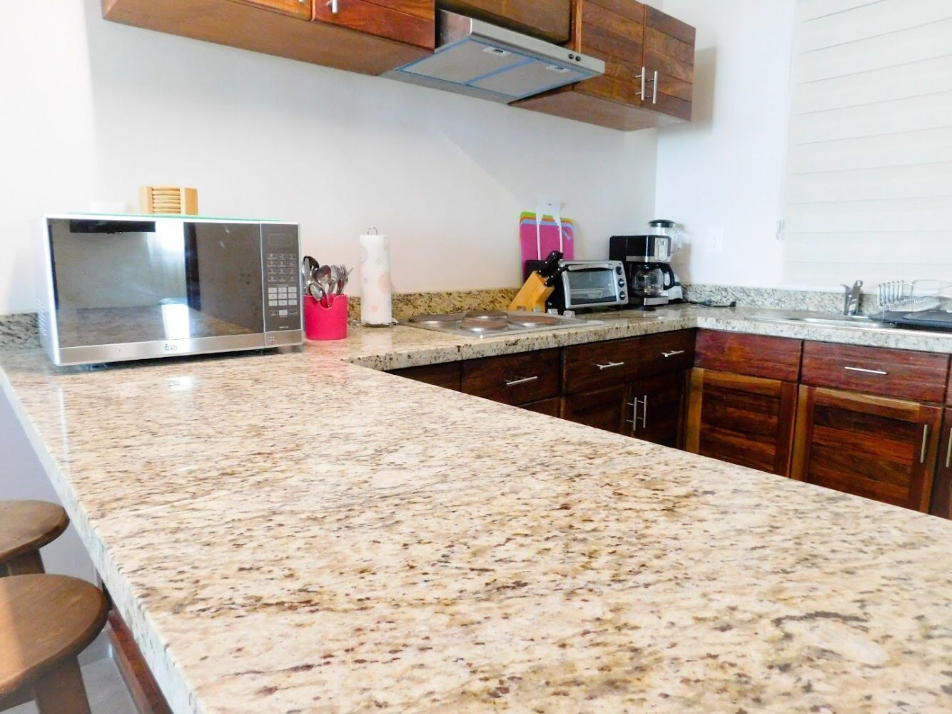 A kitchen with granite countertops, stainless steel appliances, wooden cabinets, and a range hood.