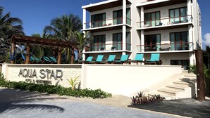 A multi-story hotel with balconies and a pool area. - Aquastar By RT Vacation Rentals (Mahahual)