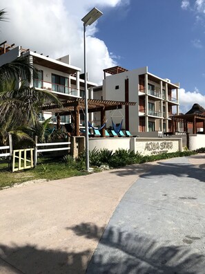 Een modern hotel met een zwembadgedeelte, buitenterras en een bord waarop 'AQUA STAR' staat.