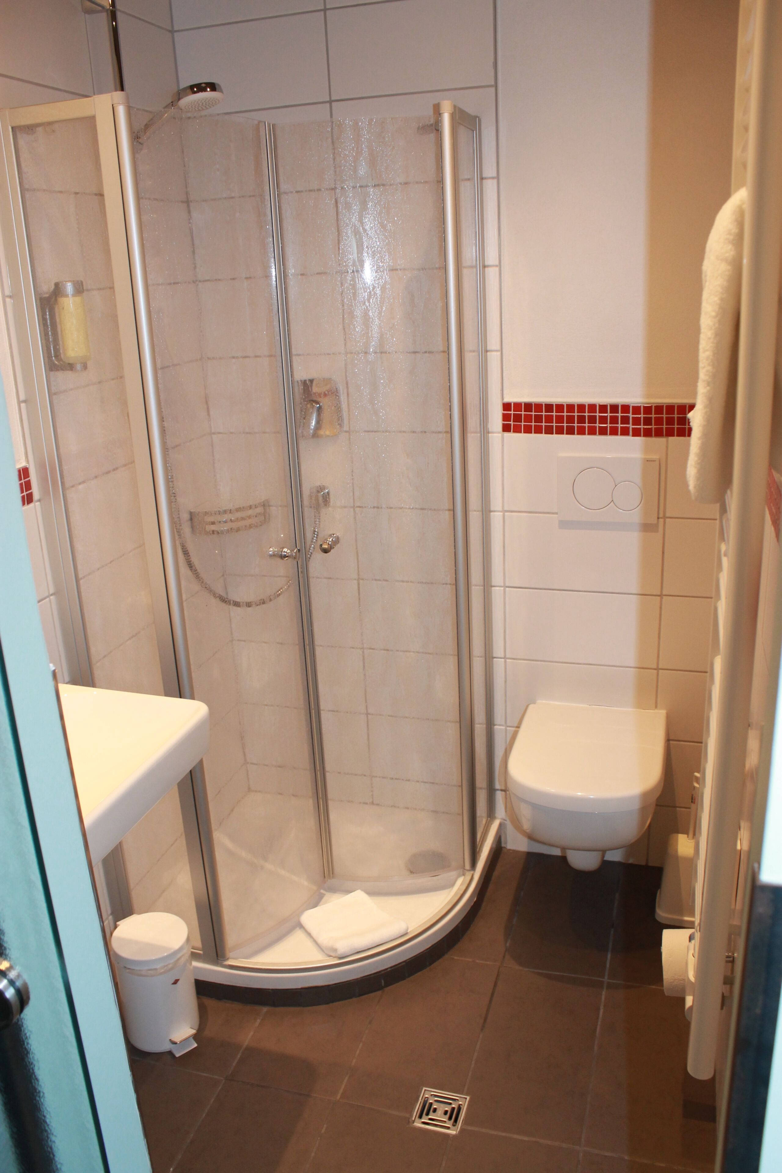 Ein Badezimmer mit einer Duschkabine, einer weißen Toilette und einem Waschbecken mit Handtuchhalter.