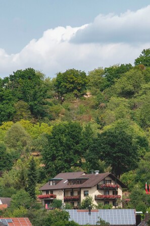 A hillside house with multiple balconies, surrounded by dense greenery. - Hotel Restaurant Martha (Wertheim)