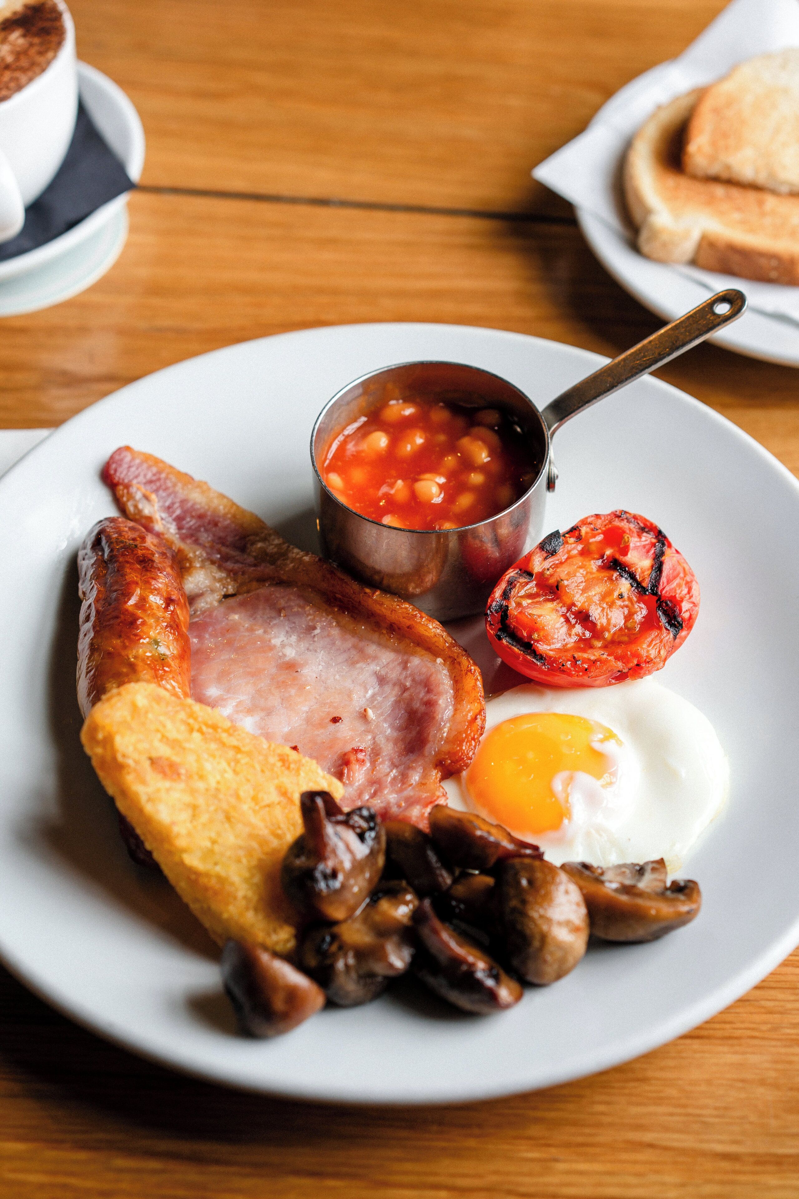 Prato de comida de café da manhã com ovos, bacon, cogumelos e feijão.