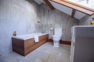 Un baño moderno con un tocador de madera, una bañera, un inodoro y una ducha.