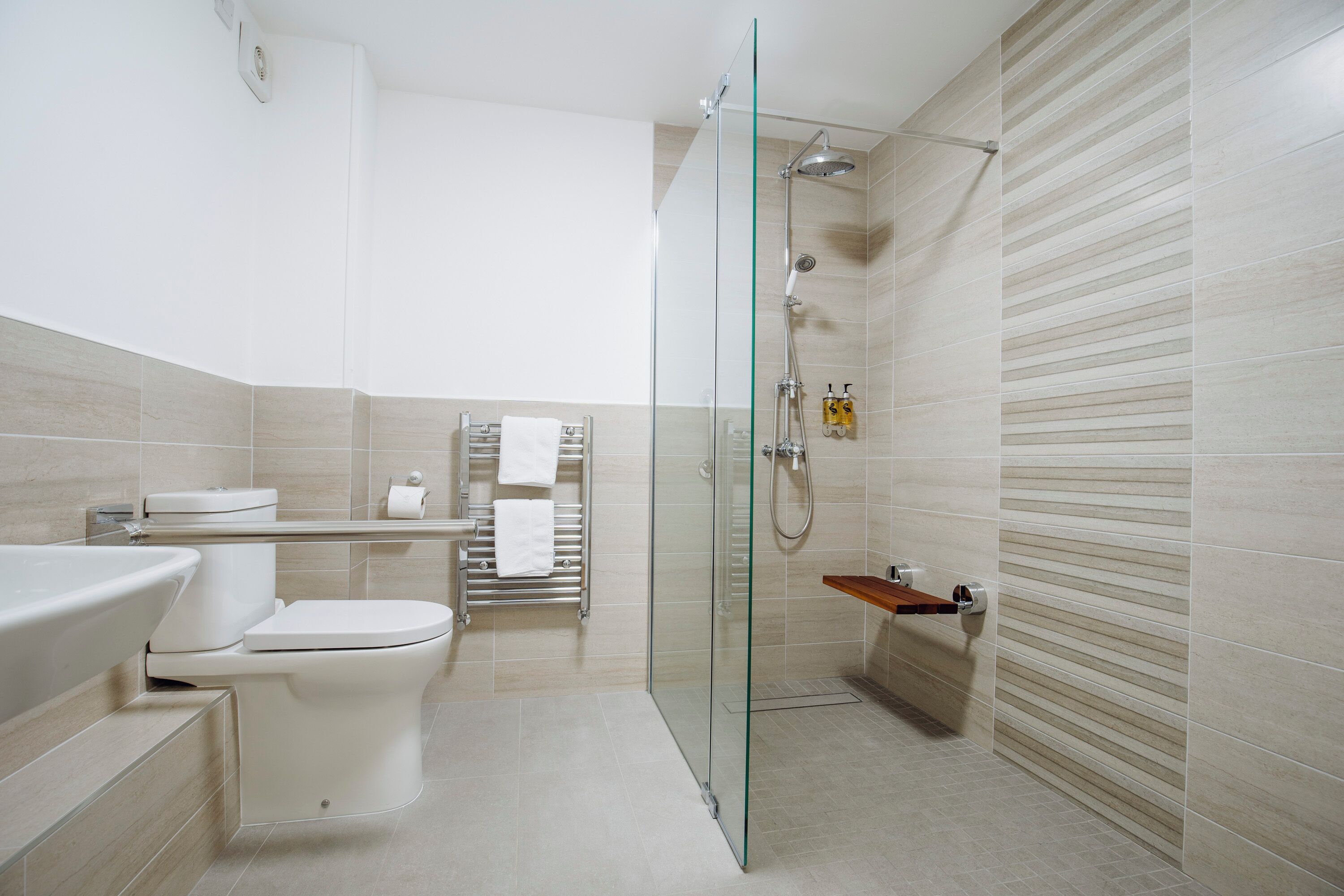 A modern bathroom with a glass-enclosed shower, a white toilet, and a bathtub.