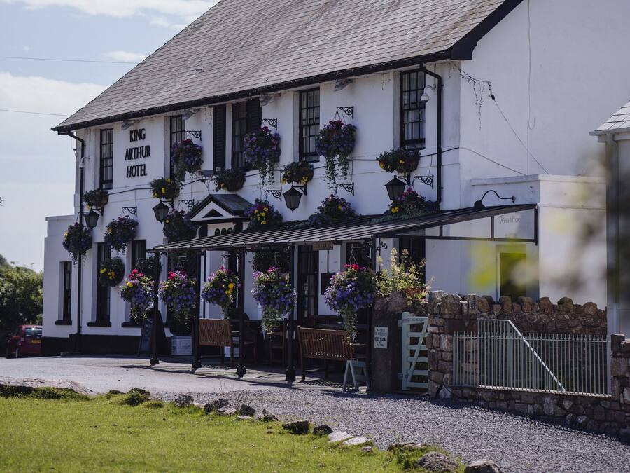 Un edificio blanco con un letrero que dice "King Arthur Hotel".