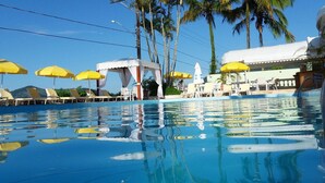 Una piscina con sombrillas amarillas, palmeras y sillas de descanso.
