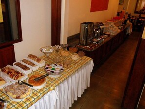 A buffet table with various food items and a coffee station. - Hotel Torremolinos (Ubatuba)