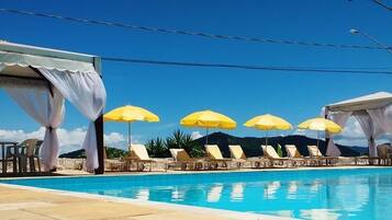 Alberca al aire libre, sombrillas en la alberca y camastros