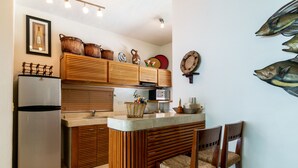 Eine Küche mit Holzausstattung, einem Kühlschrank, einer Spüle und einer Bar mit Stühlen.
