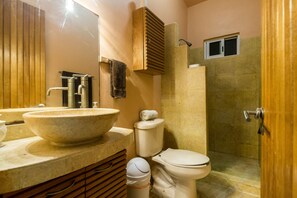 Een badkamer met een groot wastafel, een toilet, een douchecabine en een houten wastafelmeubel.
