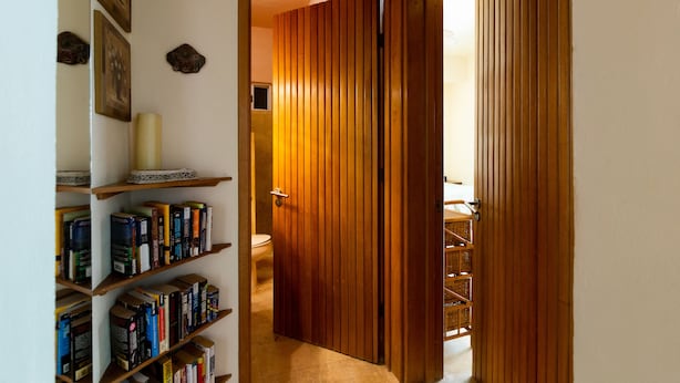 Ein Flur mit Holztüren, einem Bücherregal und einer Toilette im Hintergrund.