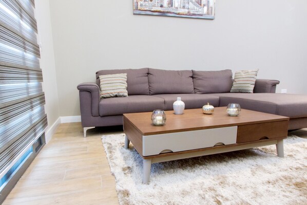 A living room with a grey sofa, a wooden coffee table, and a fluffy rug.