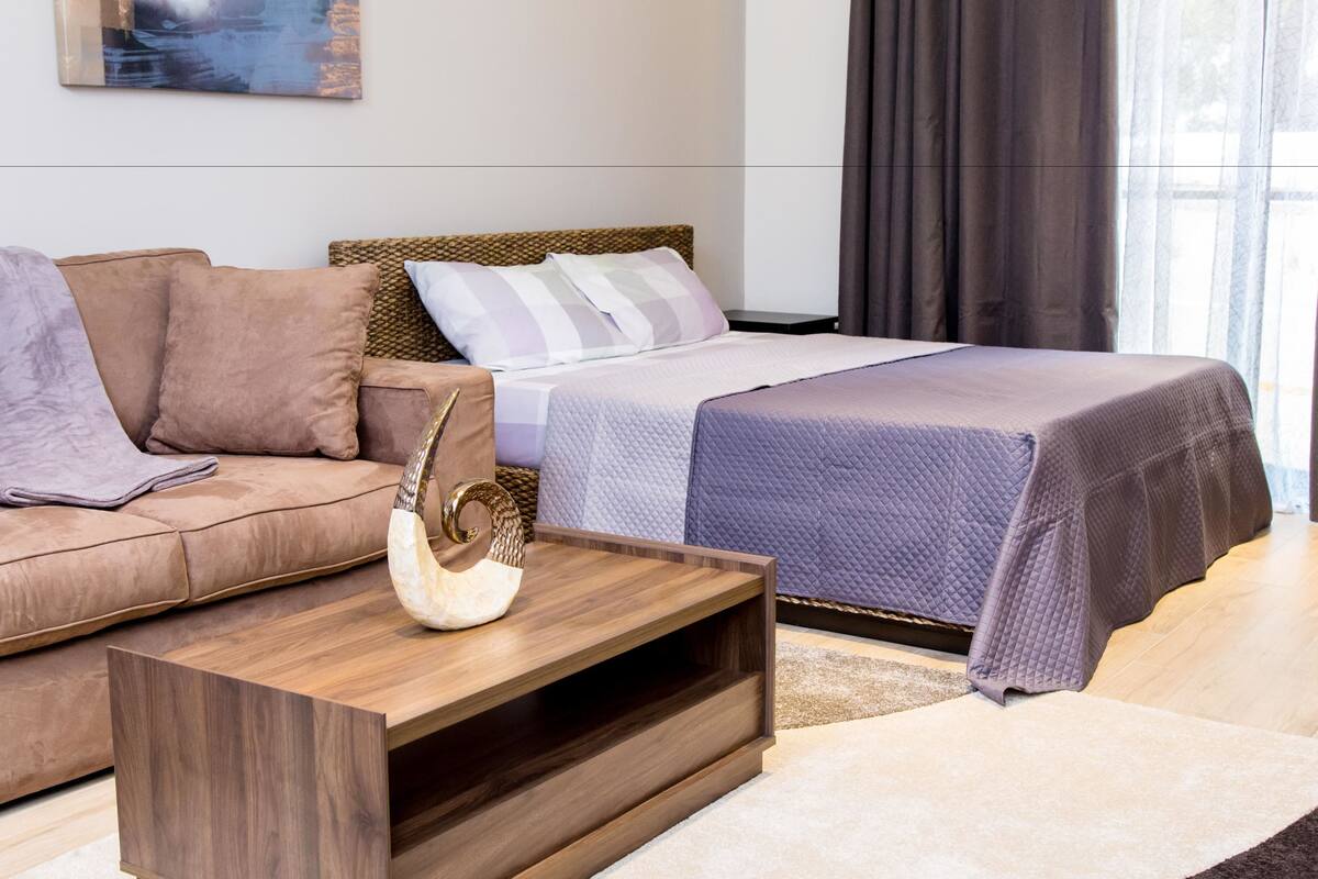 A modern bedroom with a bed, a sofa, and a wooden coffee table.