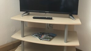 Een televisie op een standaard, met afstandsbediening en tijdschriften op het onderste plank.