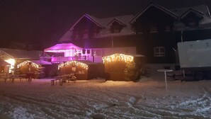 Een besneeuwde buitenruimte met een gebouw, een balkon en een overdekte zithoek.