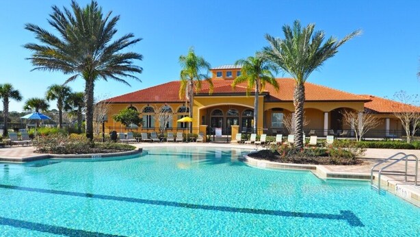 A hotel with a large pool, palm trees, and a red-tiled roof. - Watersong Resort 122GTCJGIE - Six Bedroom House (Davenport)