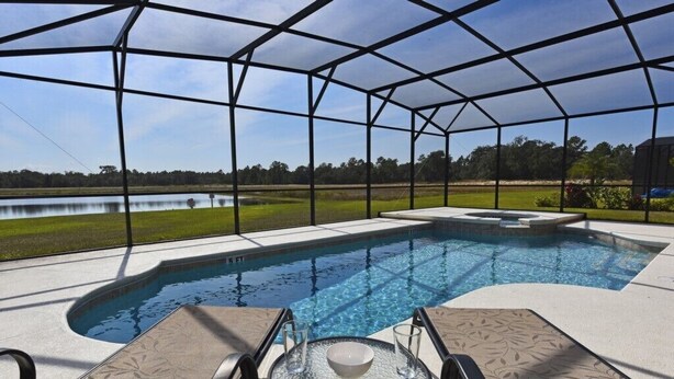 A swimming pool with a covered area, lounge chairs, and a table with a bowl.