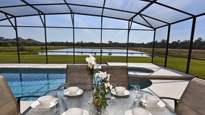 A covered outdoor dining area with a view of a lake and hills.