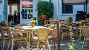 An outdoor seating area with wicker furniture, potted plants, and umbrellas.