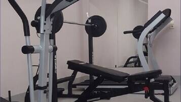 A gym with exercise equipment including a treadmill, weight bench, and a rowing machine.