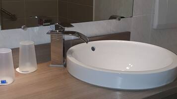 A bathroom with a white sink, a mirror, and a wooden vanity.