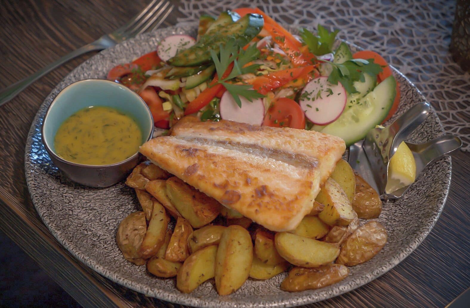 A plate with fish, potatoes, and a salad.