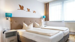 A double bed with white bedding, a grey headboard, and two bedside tables with blue lamps.