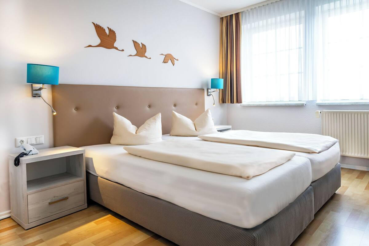 A double bed with white bedding, a grey headboard, and two bedside tables with blue lamps.