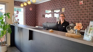 A reception desk with a modern design, a Dell computer, and decorative items including flowers and a vase.