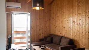 A wooden-paneled room with a brown sofa, a small table, and a computer monitor. - Luxury Loft Lefkas (Lefkada)