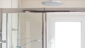 A glass-enclosed shower with a handheld showerhead and a wall-mounted faucet. - Luxury Loft Lefkas (Lefkada)