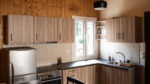A kitchen with wooden cabinets, a refrigerator, stove, and a sink. - Luxury Loft Lefkas (Lefkada)