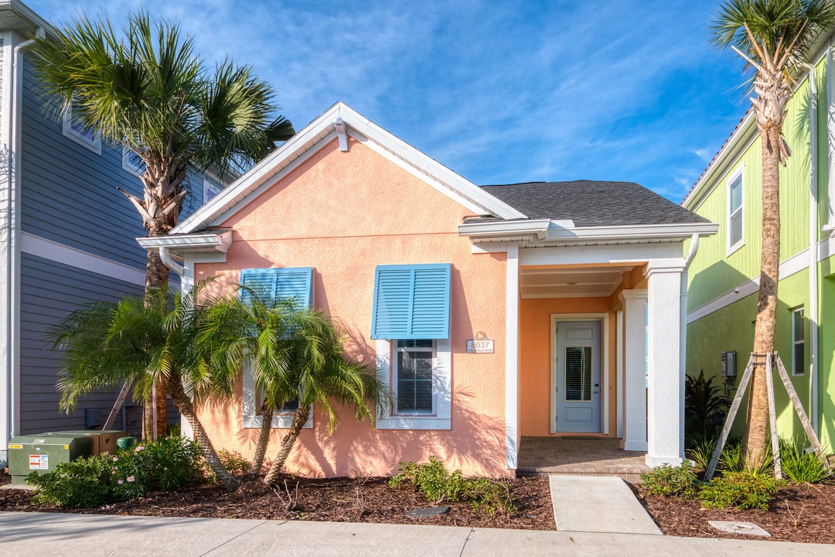 A two-story house with a peach exterior, blue shutters, and a small porch.