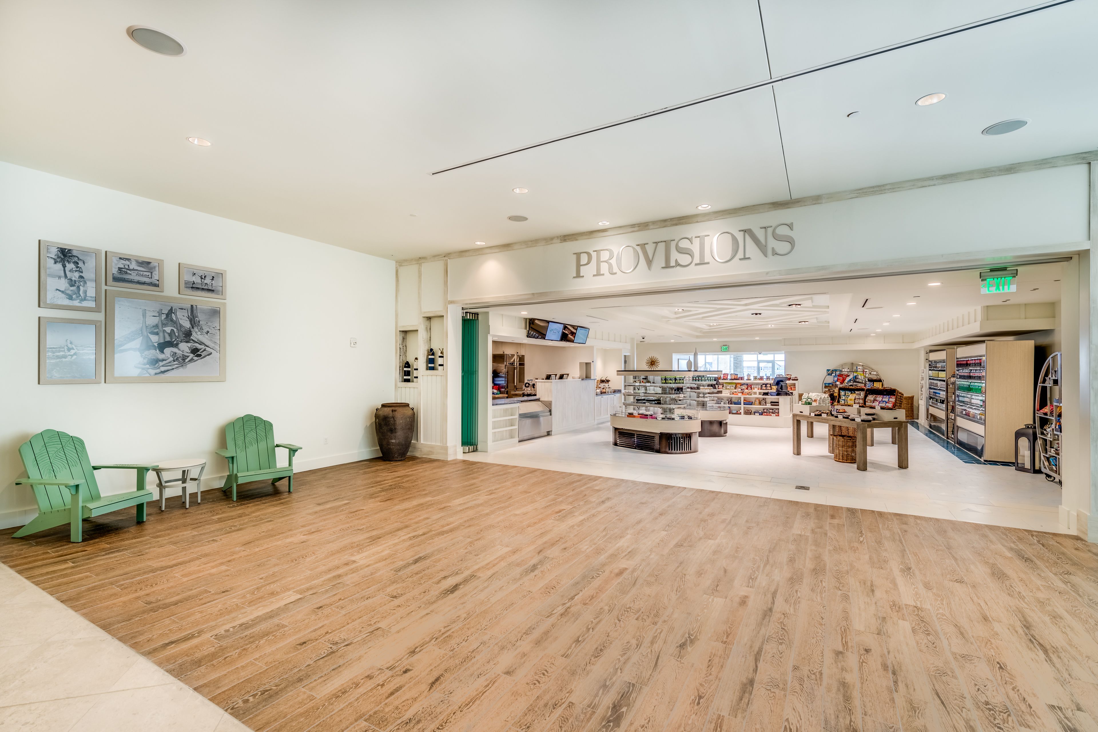 A spacious store with a wooden floor, green Adirondack chairs, and a sign reading "PROVISIONS".