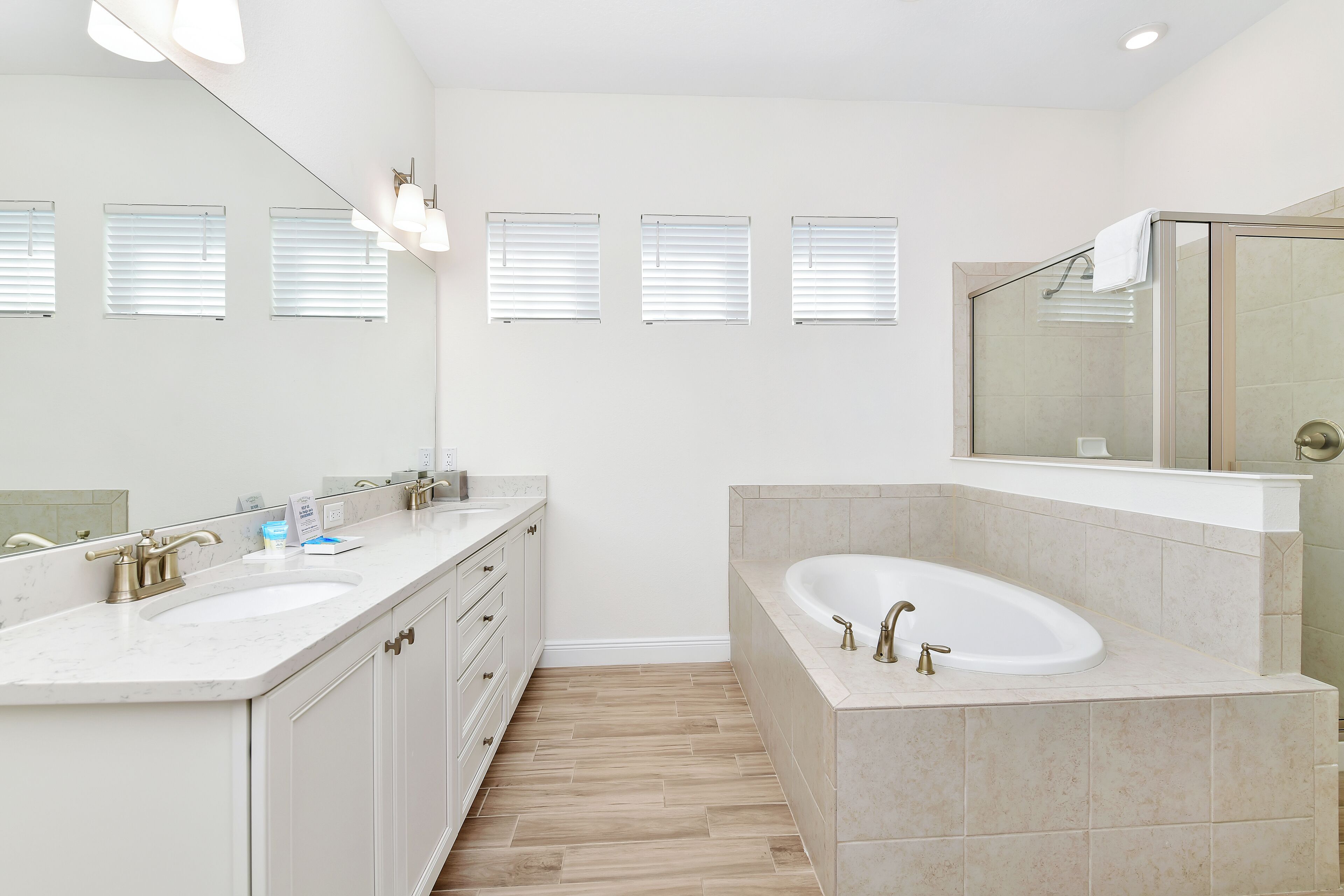 A modern bathroom with two sinks, a large bathtub, and a glass-enclosed shower.