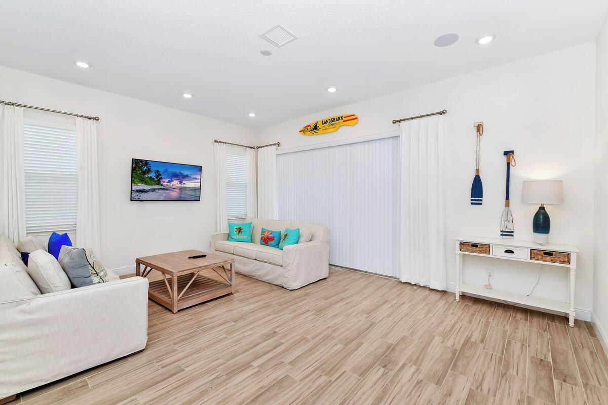 A modern living room with a sofa, coffee table, and a painting of a beach scene.