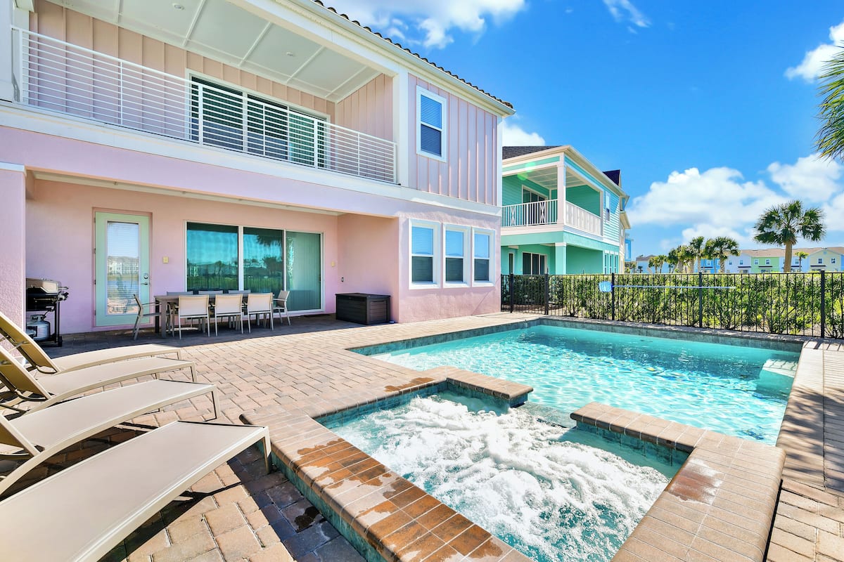 A swimming pool with lounge chairs, a hot tub, and a patio area with outdoor furniture.