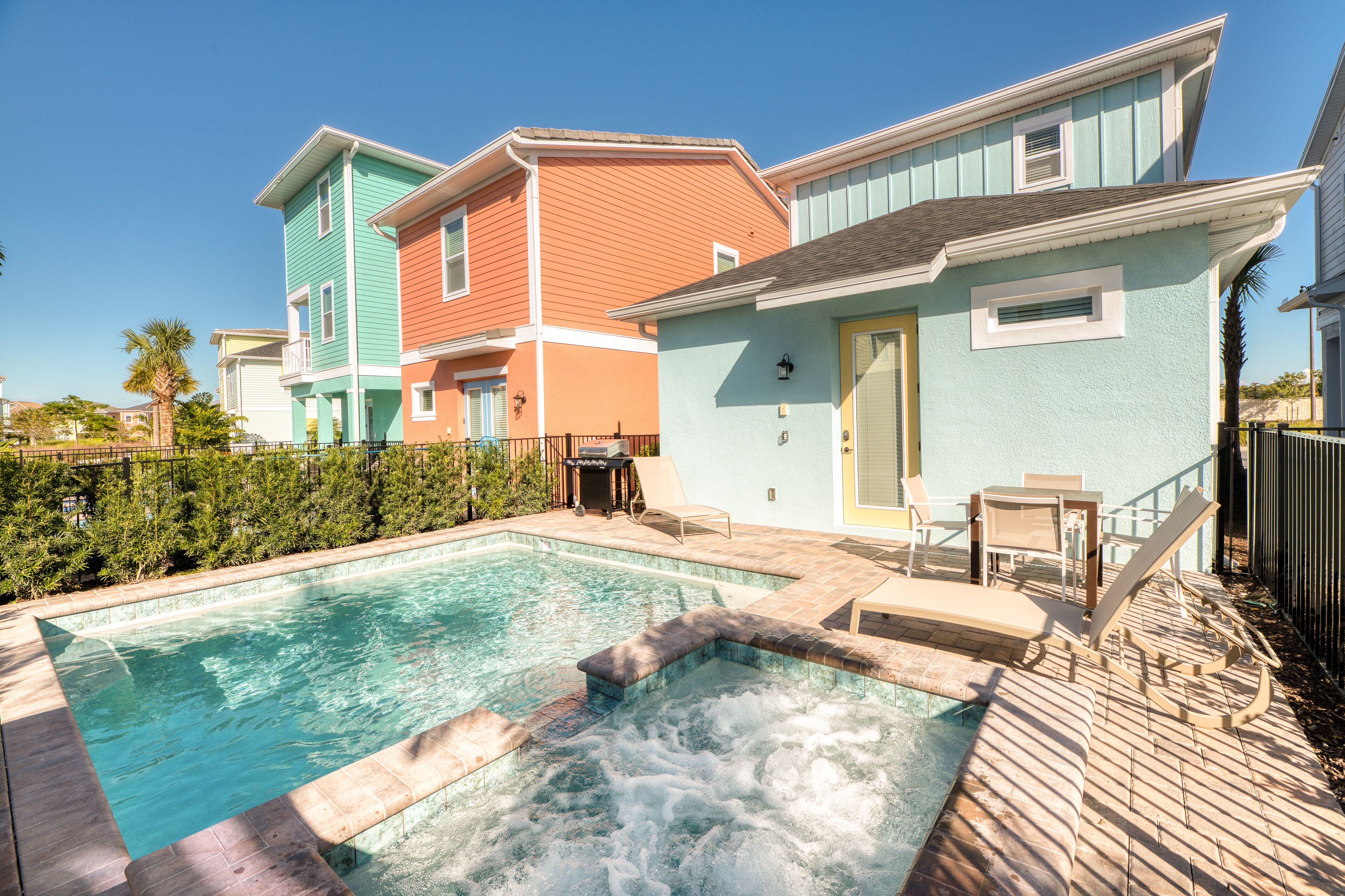 Una piscina con hidromasaje, rodeada de casas coloridas y una terraza de madera.