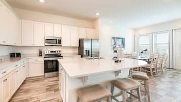 A modern kitchen with white cabinetry, stainless steel appliances, and a large island with bar stools.