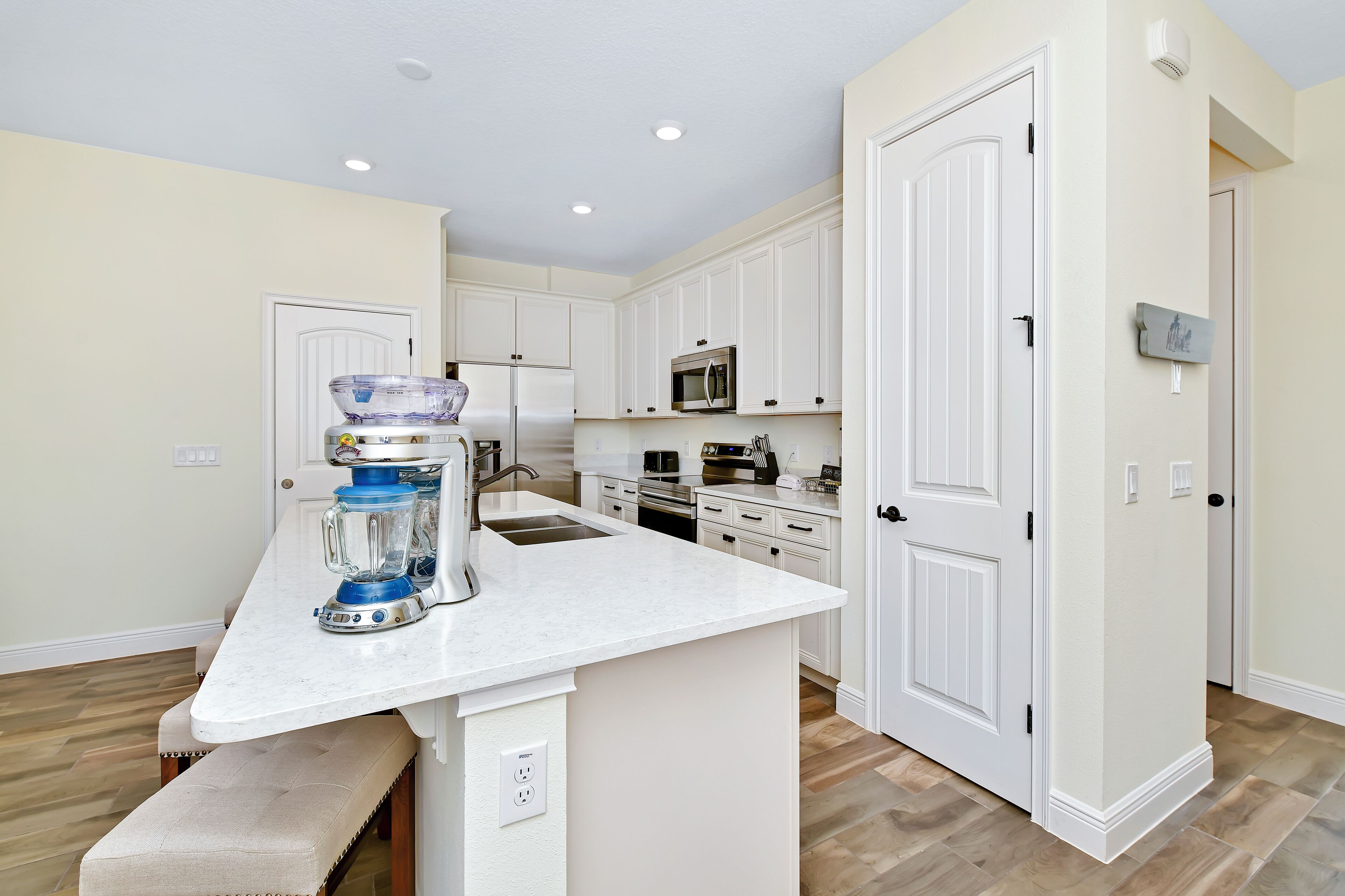 A kitchen with white cabinets, a marble countertop, and a built-in oven.