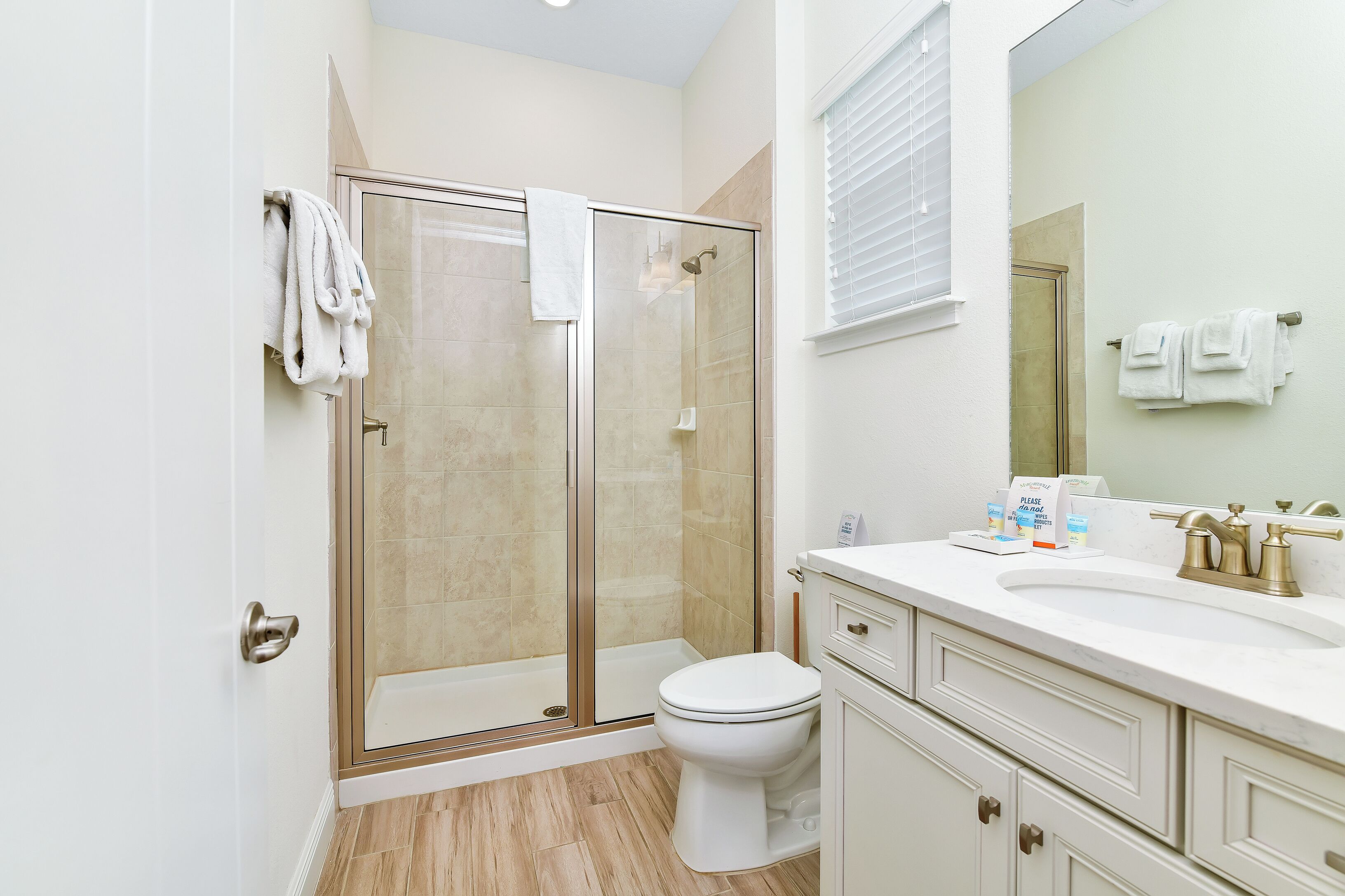 Un baño moderno con ducha envuelta en vidrio, inodoro y tocador con lavabo y espejo.