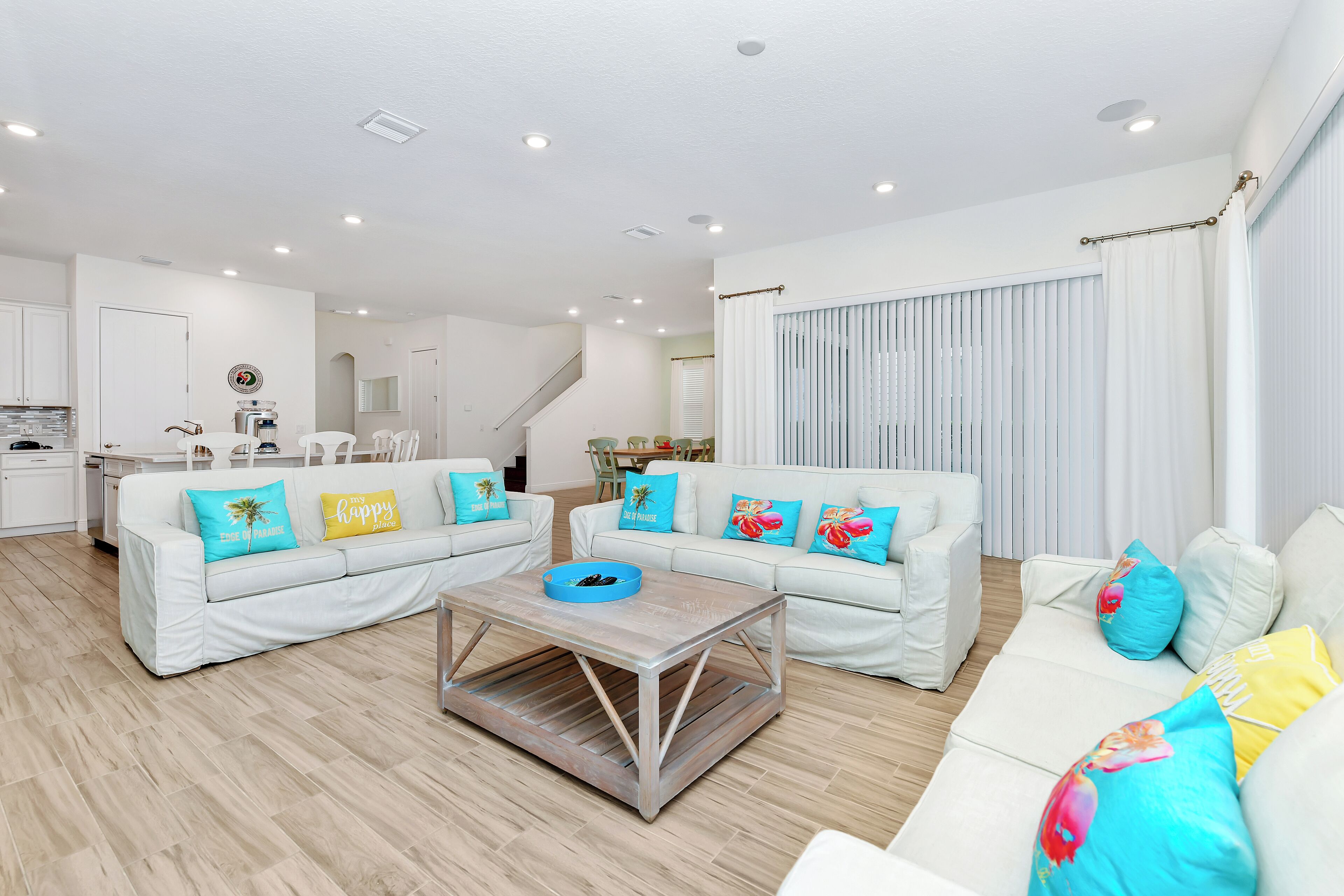 Un salón moderno con sofás blancos, una mesa de centro y almohadones coloridos.