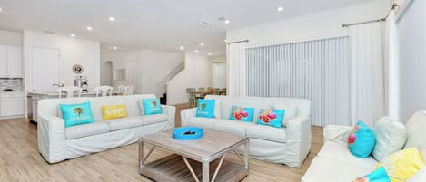 Un salón moderno con sofás blancos, una mesa de centro y almohadones coloridos.