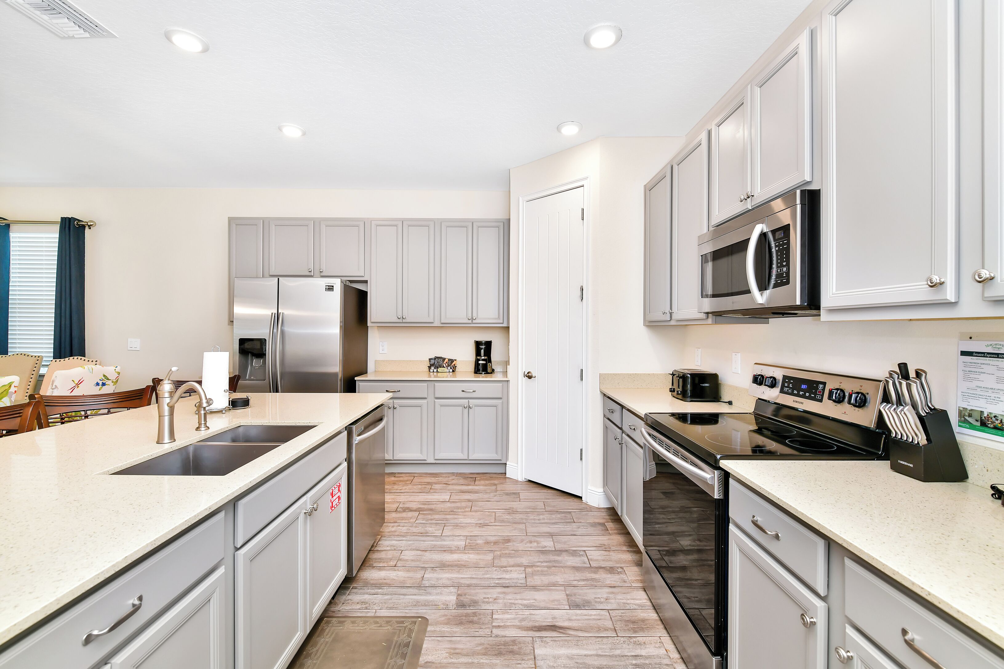 A modern kitchen with stainless steel appliances, grey cabinetry, and a large island.