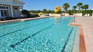 A swimming pool with clear water, surrounded by a brick deck and palm trees. - Providence 2323EVDIL - Five Bedroom House (Davenport)