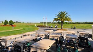 A golf course with a parking area, flags, and a palm tree. - Providence 2323EVDIL - Five Bedroom House (Davenport)